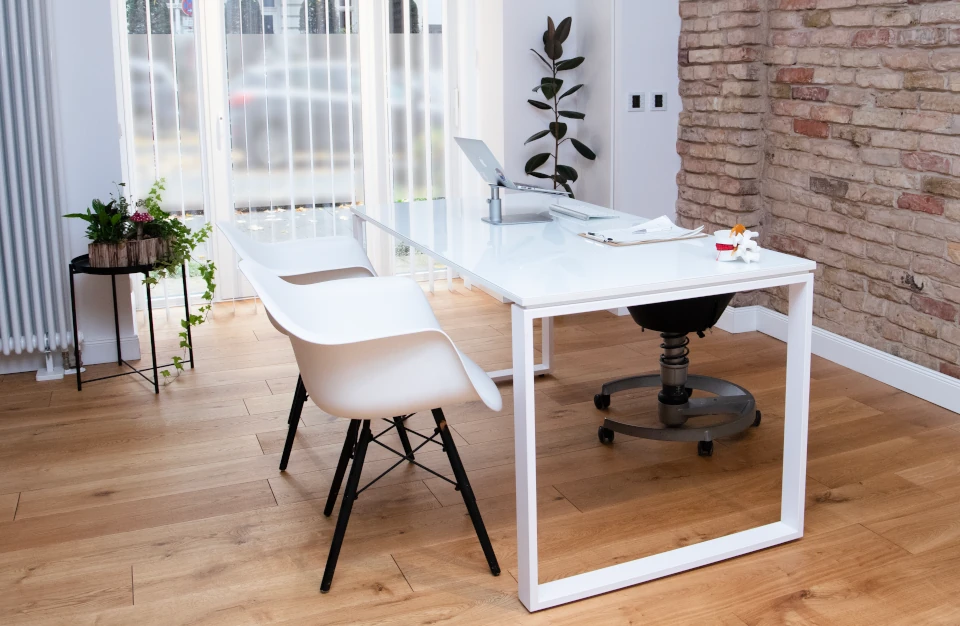 Klares Weiß, warmes Holz und eine natuerliche Backstein-Wand dominieren in der Einrichtung des Behandlungszimmer.