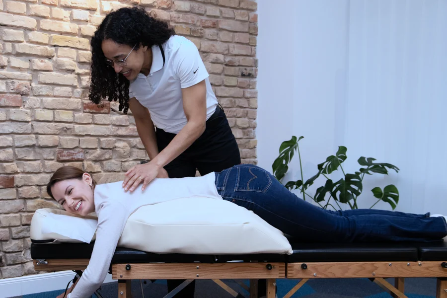 Aimee Carroll gently treating the back of a patient lying comfortably on the special pregnancy pillow.